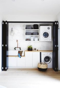 a washer and dryer in a small room with white cabinets, black trim