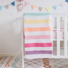 a crocheted blanket is hanging on the wall next to a white crib