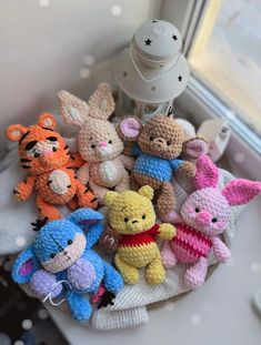 small crocheted stuffed animals sitting on top of a white cloth covered table next to a window