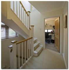 the stairs lead up to an office area in this home with carpeted flooring and white walls