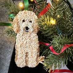 a dog ornament hanging from a christmas tree with lights in the back ground