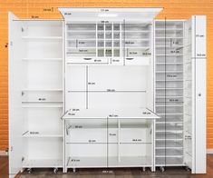 an open white cabinet with shelves and drawers on wheels in front of a brick wall