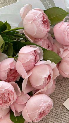 a bunch of pink flowers sitting on top of a table next to a white envelope