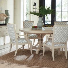 a dining room table with four chairs and a potted plant in the corner on top of it