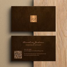 two brown business cards sitting on top of a wooden table