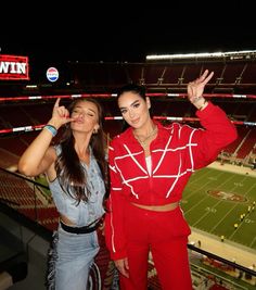 two women standing next to each other at a football game