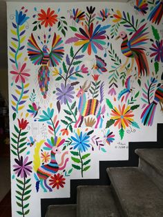 an artisticly painted mural on the side of a stairway case with flowers and birds