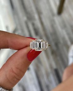 a woman's hand holding an engagement ring with three baguetts on it