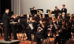 a group of people playing musical instruments in front of a stage full of other musicians