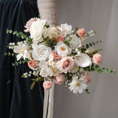 a bridal bouquet with pink and white flowers is held by a woman's arm