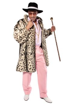 a man in a leopard print coat and pink pants with a cane posing for the camera