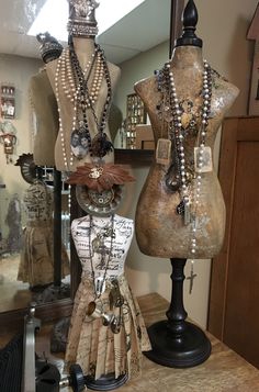 two mannequins with necklaces on display in front of a mirror