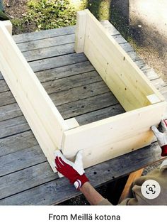 someone is working on building a wooden planter box with one hand and two hands