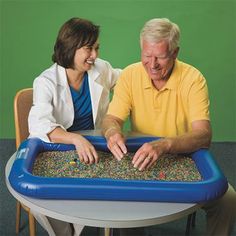 an older man and young woman playing with a game in a play table on the floor