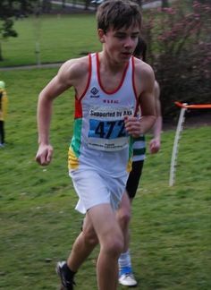 a young man running in a race on the grass