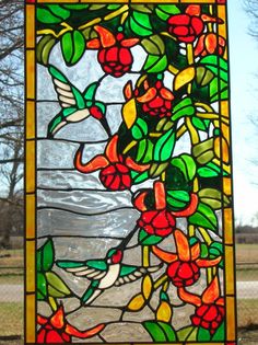 a stained glass window with red flowers and green leaves on the outside, hanging from a chain