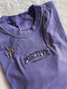 POSITIVE VIBES ONLY! super trendy embroidered tshirt! pair it with your favorite denim shorts or leggings. floral design with self love quote 💜 get summertime fine with a pop of color!  This T-Shirt is available in 5 colors: Ash Gray, Grape Purple, Emerald, Wine, and Carribean Blue. If there is a color you have in mind other than the ones available, send me a message and I can help! -Sweatshirt brand: Comfort Colors -Sizes available: Adult Small - Adult 2XL -Fit: slightly oversized fit - I'd su Trendy Crew Neck T-shirt With Embroidered Text, Trendy Purple Everyday Top, Trendy Summer T-shirt With Embroidered Text, Trendy T-shirt With Embroidered Text For Summer, Trendy Short Sleeve Tops With Letter Embroidery, Trendy Embroidered Summer T-shirt, Spring Embroidered T-shirt For Streetwear, Streetwear Short Sleeve Tops With Letter Embroidery, Embroidered T-shirt For Spring Streetwear