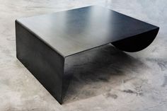 a black coffee table sitting on top of a cement floor