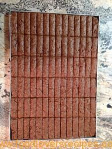 a square piece of chocolate cake sitting on top of a white countertop next to a wall