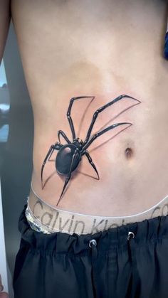 a woman's stomach with a black spider tattoo on her lower back and side