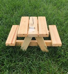 a picnic table made out of wooden planks in the grass with a knife sticking out of it