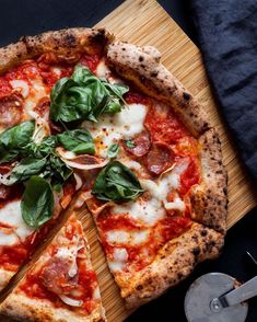 a pizza sitting on top of a wooden cutting board next to a knife and fork