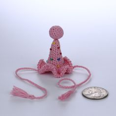 a small crocheted doll sitting next to a coin