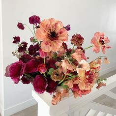 a bunch of flowers that are sitting in a vase on a table next to some stairs