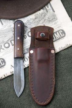 a knife and sheath sitting next to each other on top of a cloth covered table