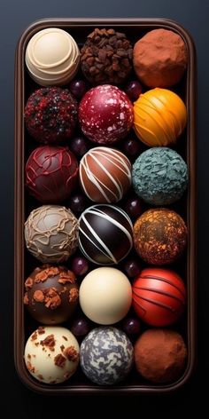 an assortment of different types of chocolates in a tray on a table with black background