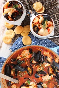 a bowl of seafood and mussels next to bread on a table with utensils