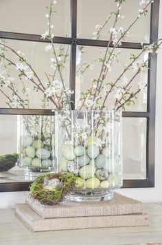 two vases filled with flowers and eggs sitting on top of a table next to a mirror