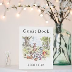 a book sitting on top of a table next to a glass vase filled with flowers