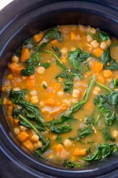 a close up of a bowl of soup with spinach and chickpeas in it