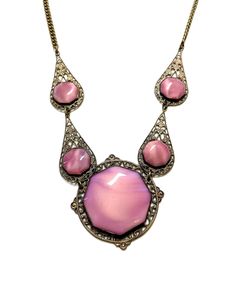 Lovely c1920s statement necklace with beautiful rose pink glass cabochons in ornate gold tone filigree links and held by brass chain.  The cabochons are all octangular in shape and pink color has a slight variegated look.  The necklace measures 22" in length and the large center stone pendant is 1.62" by 1.62". The overall condition is considered to be very good with only minor wear consistent with the age of the piece and gentle use. Filigree Necklaces, Beautiful Rose, Pink Glass, Brass Chain, Stone Pendant, Rose Pink, Beautiful Roses, Stone Pendants, Pendant Necklaces