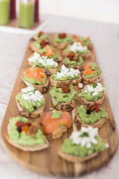 small appetizers are arranged on a wooden platter with white and green toppings