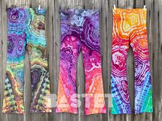 three pairs of colorful leggings hanging on a wooden fence next to each other