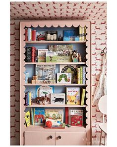 a pink bookcase with many books on it in a child's playroom