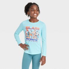 The Tune Squad Slam Dunk Long-Sleeve Graphic T-Shirt is perfect for any fan of the sports comedy series and film. Your child will look cute and feel comfortable all day in this pullover jersey tee, thanks to its soft fabric construction. A cheerful illustration of the Tune Squad characters in their jerseys, along with the glitter-detailed text "Slam Dunk," accents the front of this long-sleeve T-shirt for a fun look. It's finished in a light aqua green shade that makes a refreshing pairing with Moisture-wicking Crew Neck Fan Apparel Top, Graphic Tee With Character Print And Long Sleeves, Casual Moisture-wicking Tops For Fan Merchandise, Sporty Cotton Tops With Cartoon Print, Sports T-shirt With Character Print And Crew Neck, Sports Long Sleeve Graphic Tee, Long Sleeve Graphic Tee For Sports, Graphic Long Sleeve Sports T-shirt, Sports Graphic Tee, Long Sleeve