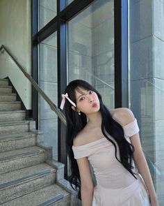 a woman with long black hair is standing on the stairs