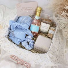 an open gift box containing body care products and personal care items on a white bed