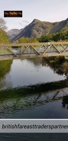 an image of a bridge over water with mountains in the backgrouds behind it