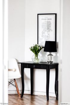 a black table with a lamp on it and a green plant sitting on top of it