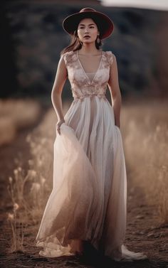 a woman wearing a dress and hat standing in the middle of a field