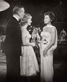 an old black and white photo of two women in formal dress talking to each other