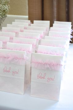 small bags with pink ruffles and thank you written on them sitting on a table