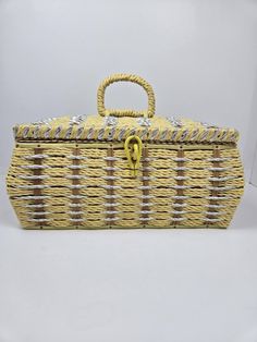 a yellow and brown basket with handle sitting on top of a white table next to a wall