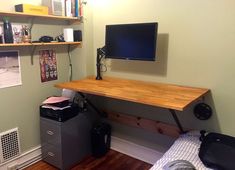 a room with a desk, bookshelf and computer monitor on it's wall