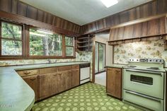 an empty kitchen with green flooring and wooden cabinets in the middle of the room