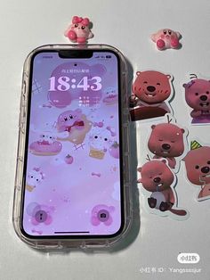 an iphone with stickers on it sitting next to some teddy bears and other items